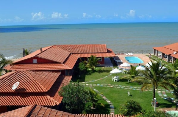 Ein Resort mit roten Dächern, einem Schwimmbad und Blick auf den Ozean.