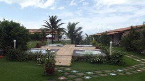 A courtyard with a central fountain, surrounded by palm trees and potted plants.