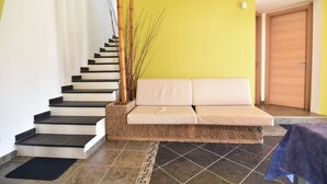 Una escalera con un banco tejido, una puerta y un piso de baldosas.