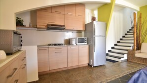 Una cocina moderna con armarios de madera, un microondas, un refrigerador y una estufa a gas.