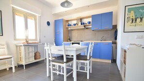 A modern kitchen with white cabinetry and a dining table set for four. - Sitting on the beach (Santa Croce Camerina)