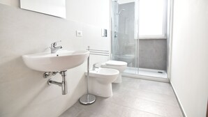 A modern bathroom with a white sink, bidet, and glass-enclosed shower. - Center Beach (Ragusa)