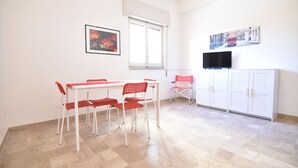 A dining area with a table and chairs, a television on a stand, and a cabinet. - Center Beach (Ragusa)
