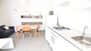 Una cocina compacta con comedor, un sofá negro y una encimera blanca.