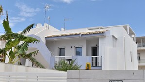 Un edificio moderno blanco con balcón, antenas parabólicas y un letrero que indica que forma parte de un complejo residencial.