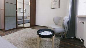 Un salon moderne avec un canapé, une petite table sur laquelle repose un plateau, un fauteuil, une porte coulissante et, au mur, une citation inspirante encadrée.