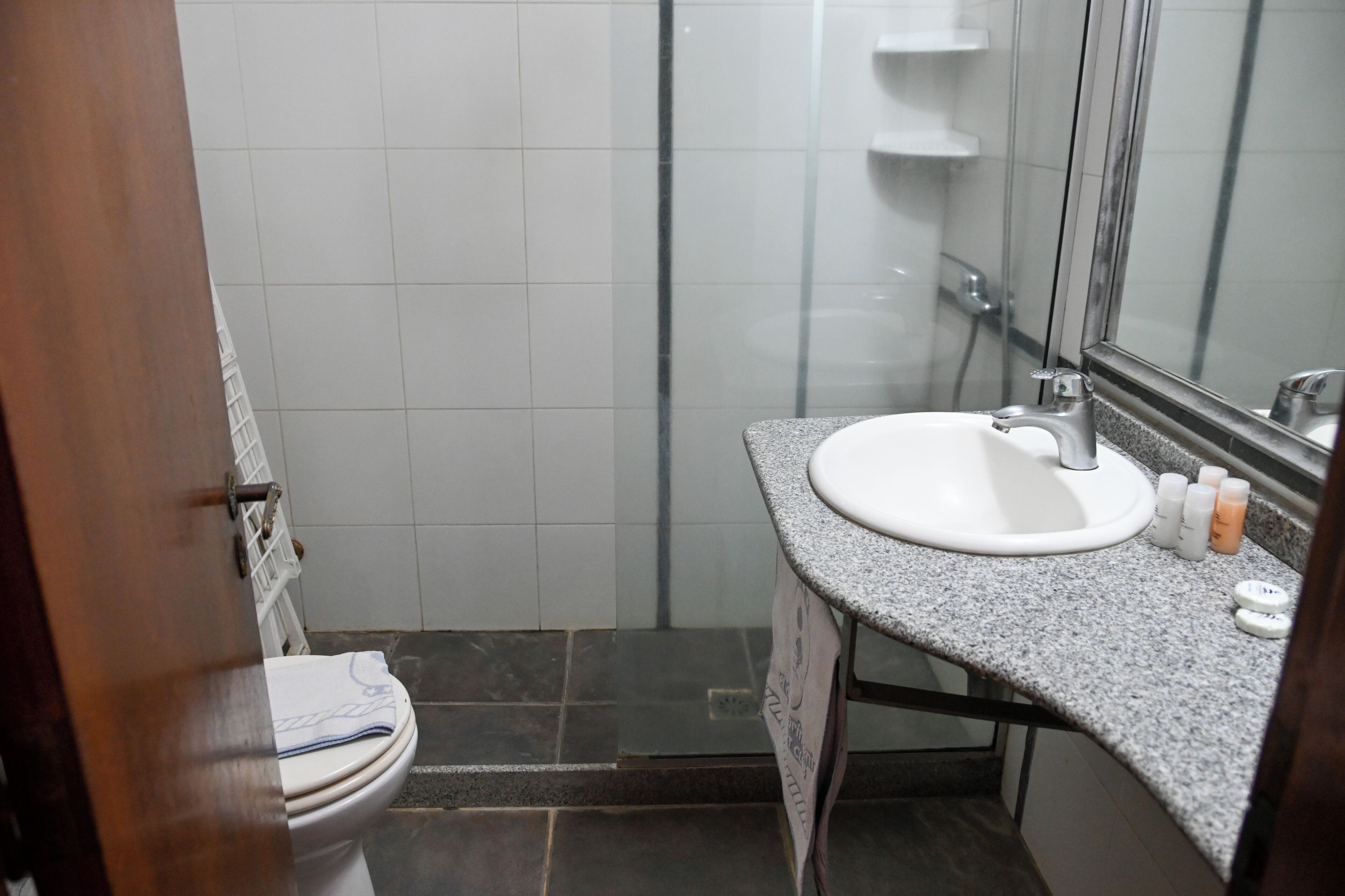 Un baño con lavamanos blanco, espejo y zona de ducha.