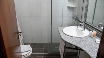 Un baño con lavamanos blanco, espejo y zona de ducha.