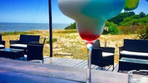 Un bar en la playa con un cóctel sobre la barra, con vistas al océano.