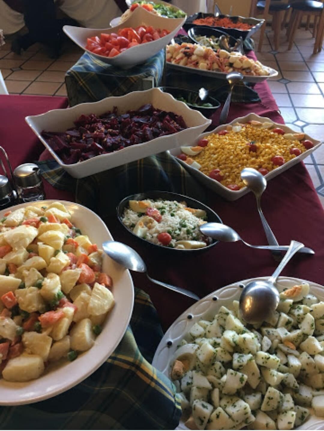 Un tavolo da buffet con diversi piatti, tra cui patate, mais e un'insalata.