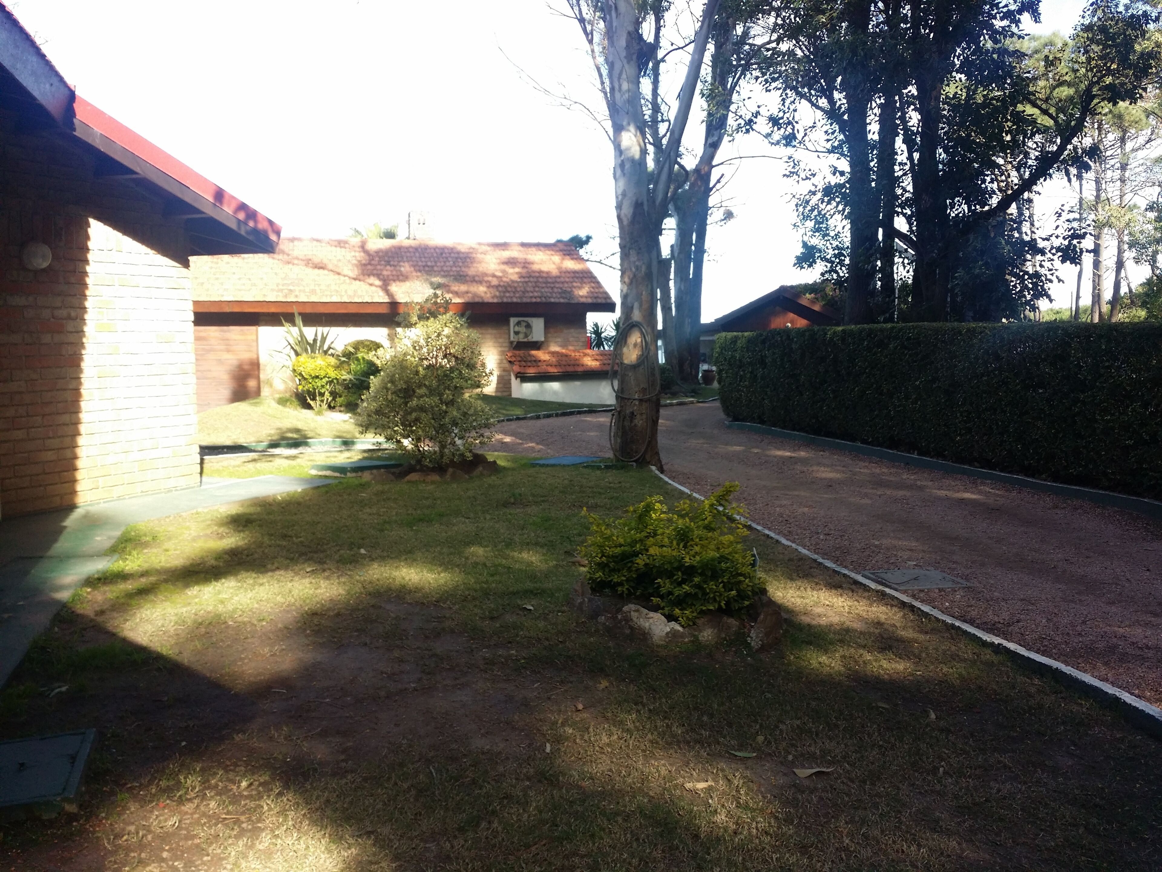 A residential area with a paved driveway, a small lawn, and a brick building with a red roof.