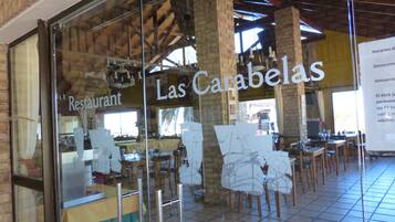 Un restaurante con fachada de vidrio, vigas de madera y piso de baldosas.