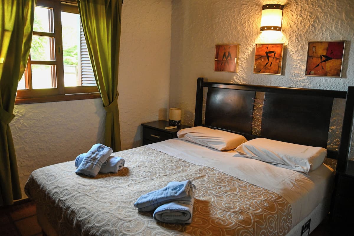A hotel room with a bed, a nightstand, a lamp, and artwork on the wall.