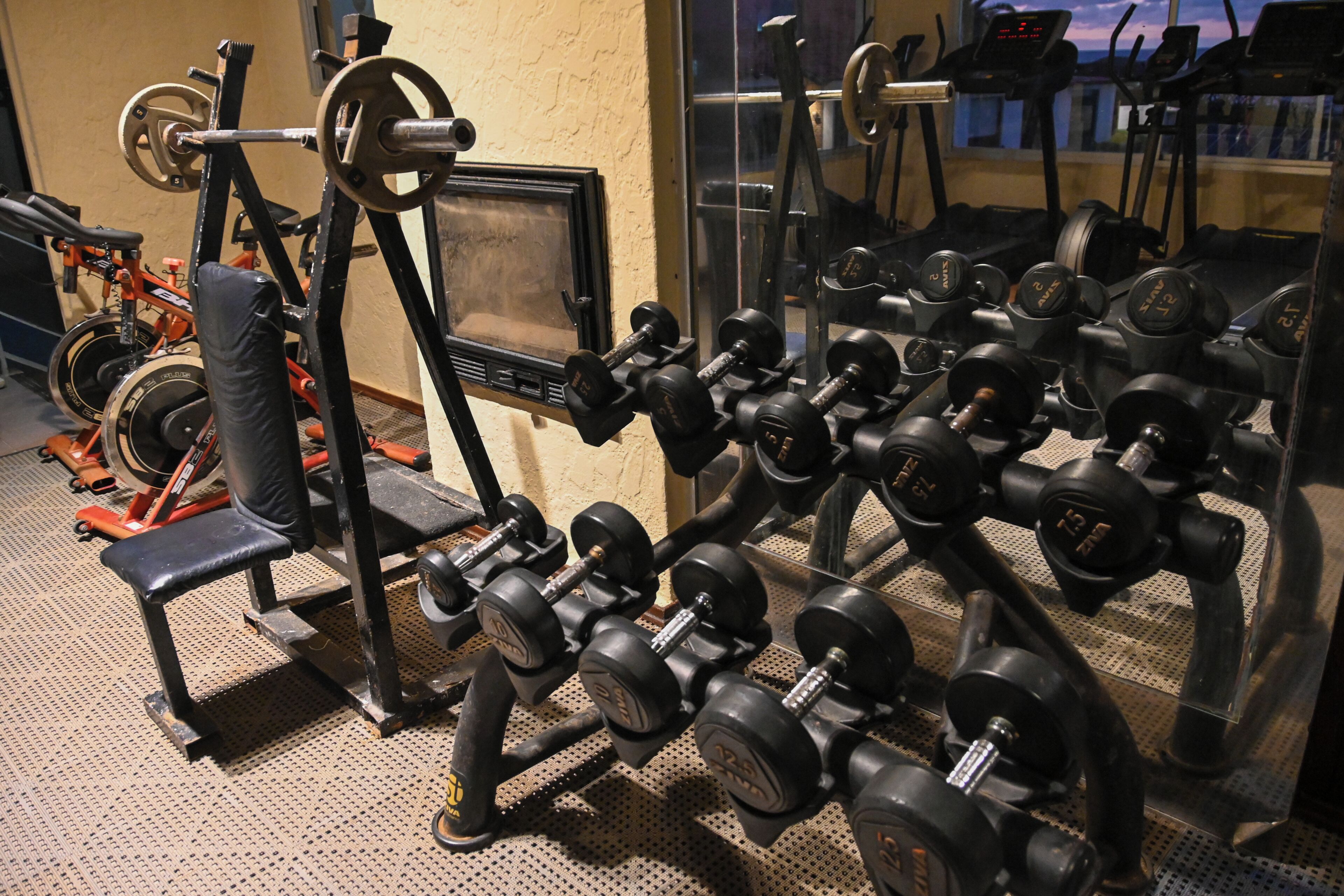 A gym with various exercise equipment, including dumbbells, a bench, and weight machines.