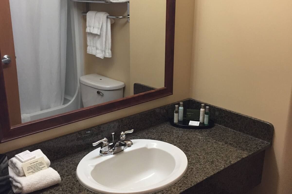 A bathroom with a sink, mirror, and towel rack.