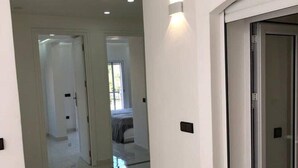 A modern interior with a glass door leading to a room, white walls, and a tiled floor. - - IMI White house 2 - (Imi Ouaddar)