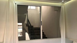 A modern living room with a built-in bench and a large sliding glass door leading to a staircase. - - IMI White house 2 - (Imi Ouaddar)
