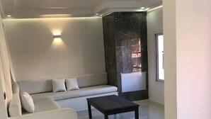 A modern living room with a white sofa, a dark coffee table, and a cat. - - IMI White house 2 - (Imi Ouaddar)