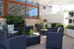 An outdoor patio area with wicker furniture, potted plants, and a stone wall. - La Corte di Sofia (Realmonte)