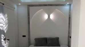 Un dormitorio moderno con una cama grande, cabecera con iluminación integrada y diseño minimalista.