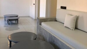 Un espacio habitable moderno y minimalista con un sofá y dos mesas redondas.