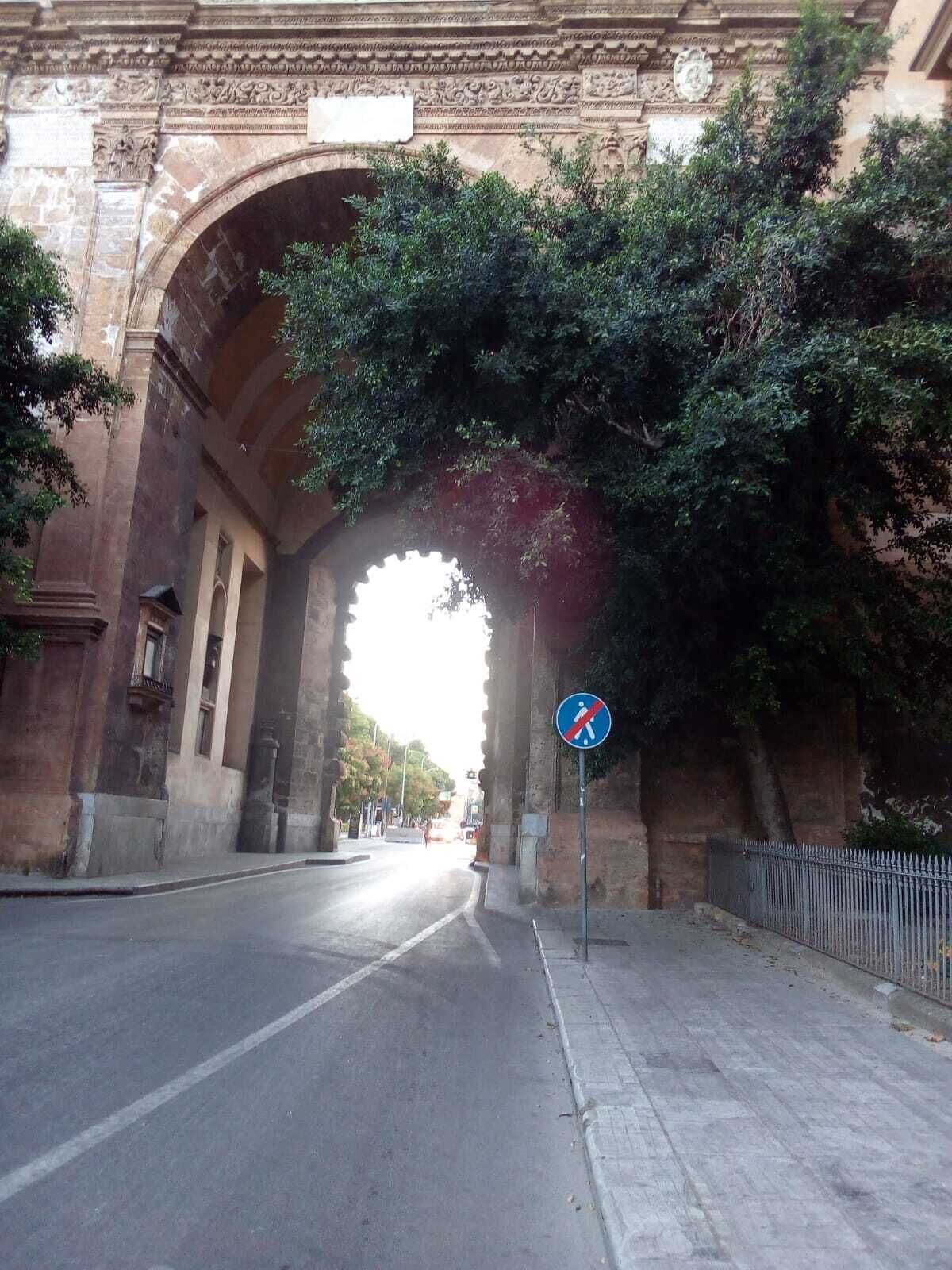 Eine gebogene Steinbrücke mit einem Fußgängerzeichen, einer Straße und einem Metallzaun.