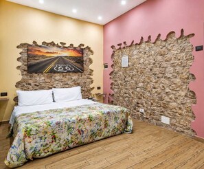 A bedroom with a bed, a painting of a road, and a stone wall. - In the Shadow of Porta Nuova (palermo)