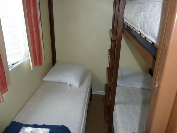 A small, compact room with two bunk beds and a single bed.