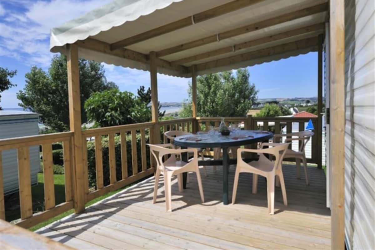 An outdoor deck with a table and chairs, a covered area, and a view of the water.