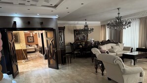 Un salón amplio con un sofá grande, una mesa de comedor y una araña.