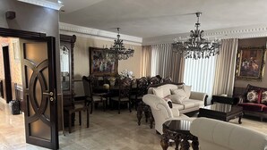 Un salón comedor amplio con una lámpara de araña grande, muebles elegantes y un área de comedor con un cuadro en la pared.