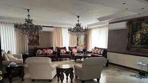 Amplia sala de estar con techo alto, candelabros ornamentados y muebles clásicos.