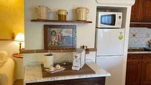 A kitchen with a white refrigerator, a microwave, a coffee maker, and shelves with various kitchenware. - Ancient village of the well "Casa La Corte" (Tramonti (SA))