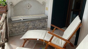 A balcony with two wooden lounge chairs and a stone wall. - Ancient village of the well "Casa La Corte" (Tramonti (SA))