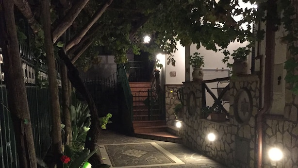 A stone pathway leading to a staircase, surrounded by greenery and illuminated by wall-mounted lights. - Ancient village of the well "Casa La Corte" (Tramonti (SA))