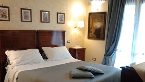 A neatly made bed with a dark bedspread and pillows, a wooden headboard, a nightstand with a lamp, and a painting on the wall. - Ancient village of the well "Casa La Corte" (Tramonti (SA))