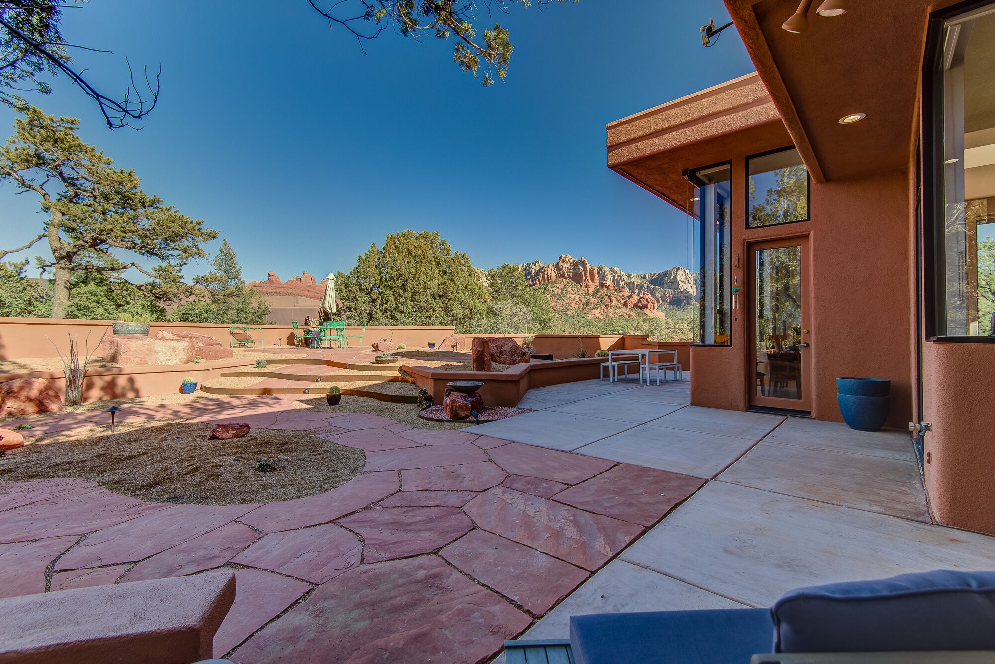 A patio with stone flooring, outdoor furniture, and a view of red rock formations.