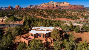 A modern house with a flat roof, surrounded by trees and a mountainous backdrop. - Experience luxury in Sedona Painted Sky—sleeps 8 with stunning panoramic views. (Sedona)