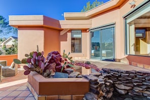 Una casa moderna con un patio, un extenso jardín de cactus y un muro de piedra.