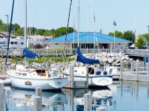 Boats docked at the marina, surrounded by calm water and a nearby building.