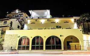 A multi-story building with a flat roof, arched windows, and a balcony.