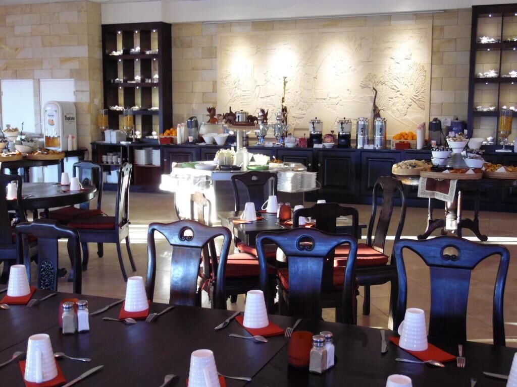 A dining area with multiple tables and chairs, equipped with disposable cups and cutlery.