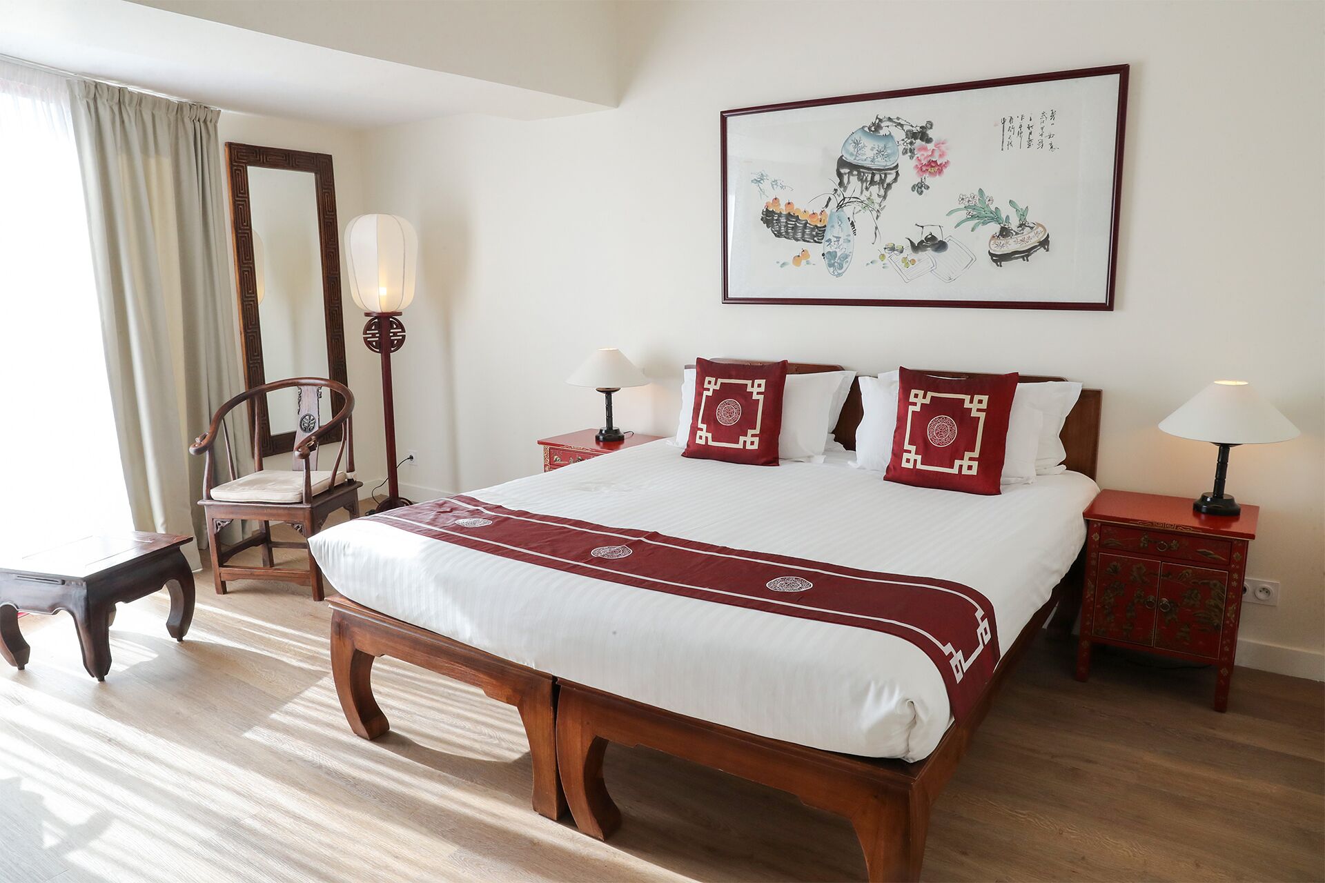 A hotel room with a large bed, two bedside tables, a chair, a mirror, and a wall-mounted artwork.