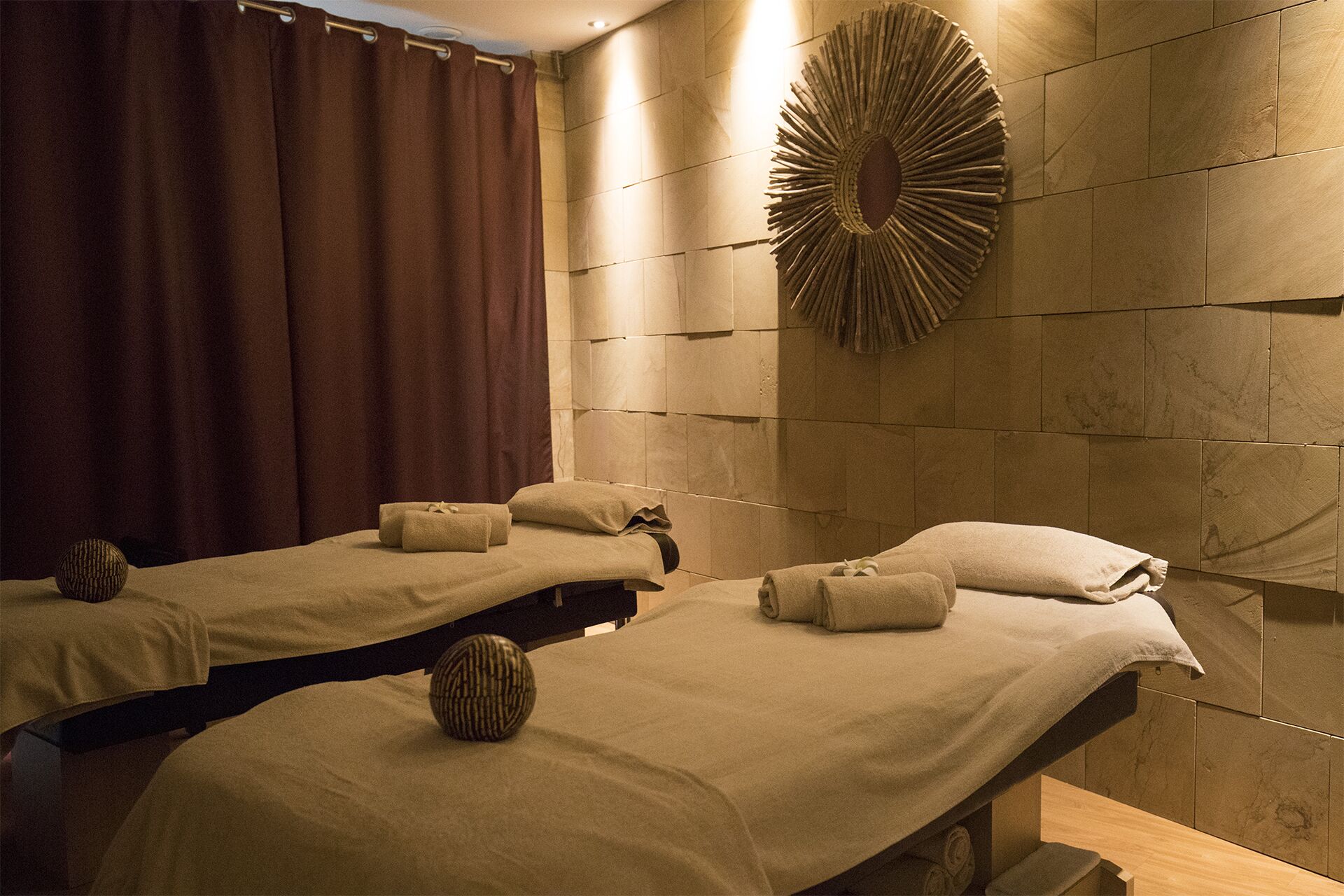 Een spa ruimte met twee massagetafels, elk met een handdoek en een gestructureerde bal.
