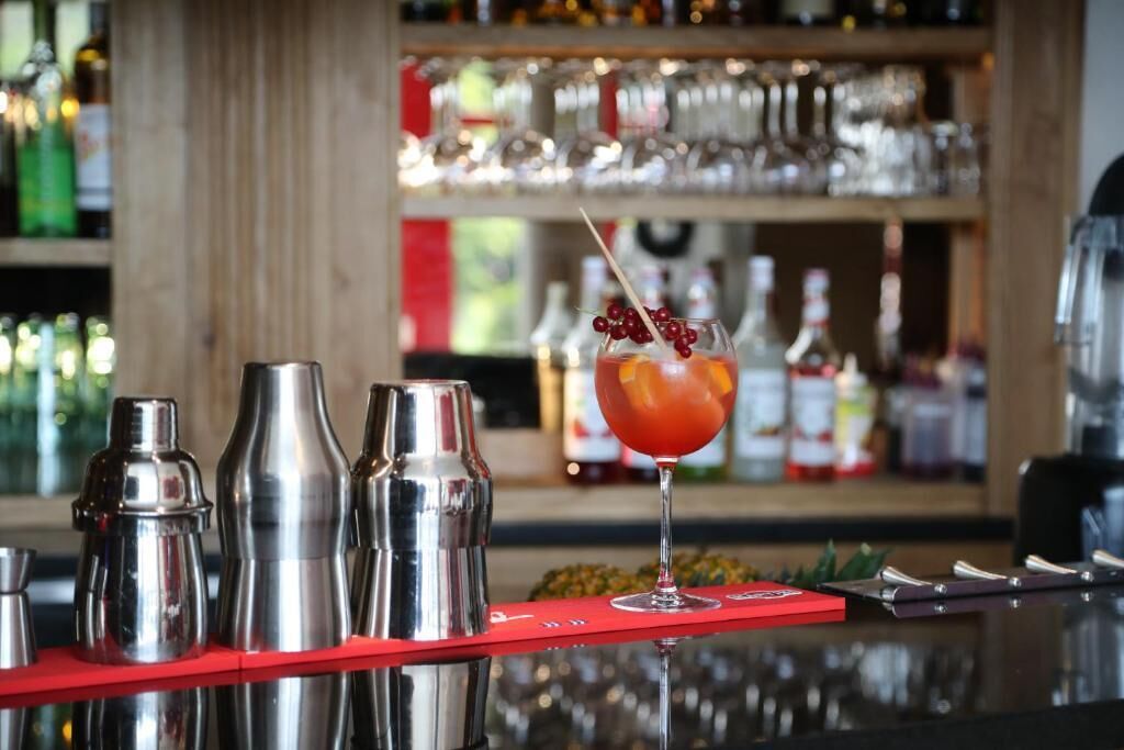 A bar area with cocktail shakers and a glass of cocktail with a garnish.