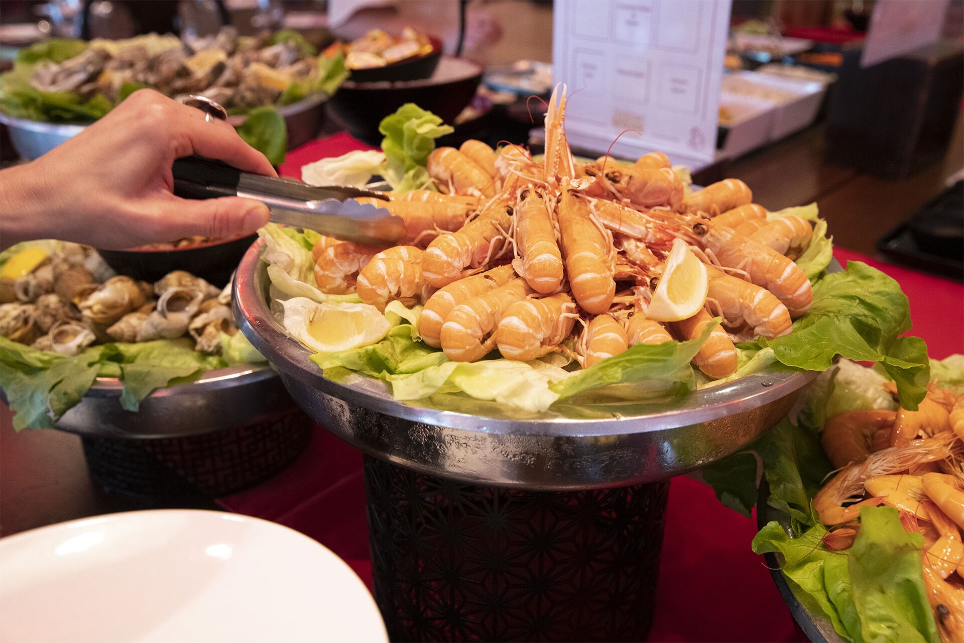 Een buffettafel met diverse gerechten, waaronder garnalen op sla en andere zeevruchten.