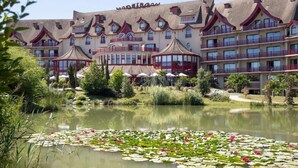 Un hôtel doté de nombreux balcons, d’une cour intérieure avec un bassin et des fleurs de lotus, et d’un style architectural traditionnel.