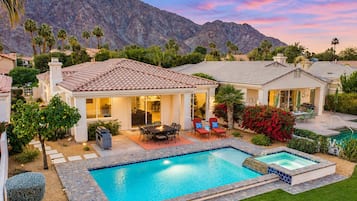 A residential property with a swimming pool, patio furniture, and a view of mountains.