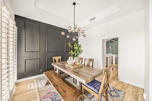 A dining room with a wooden table, chairs, a chandelier, and a plant. - Casa Havana  Stunning Views Pool Spa PGA West 4br (La Quinta)