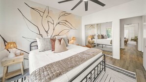 A bedroom with a bed, bedside tables, a ceiling fan, and a large mirror. - Casa Havana  Stunning Views Pool Spa PGA West 4br (La Quinta)